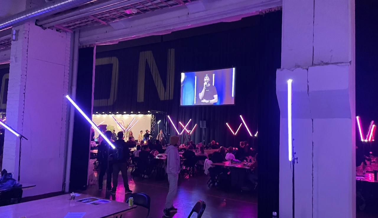 A photo showing the indoor event location at the old cable factory with a large screen streaming the opening ceremony