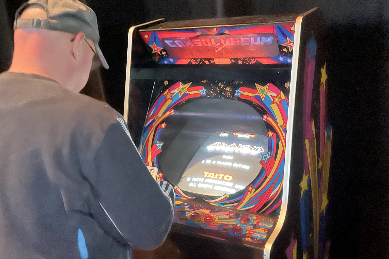Arcade machines at Revision in a colorful event space.