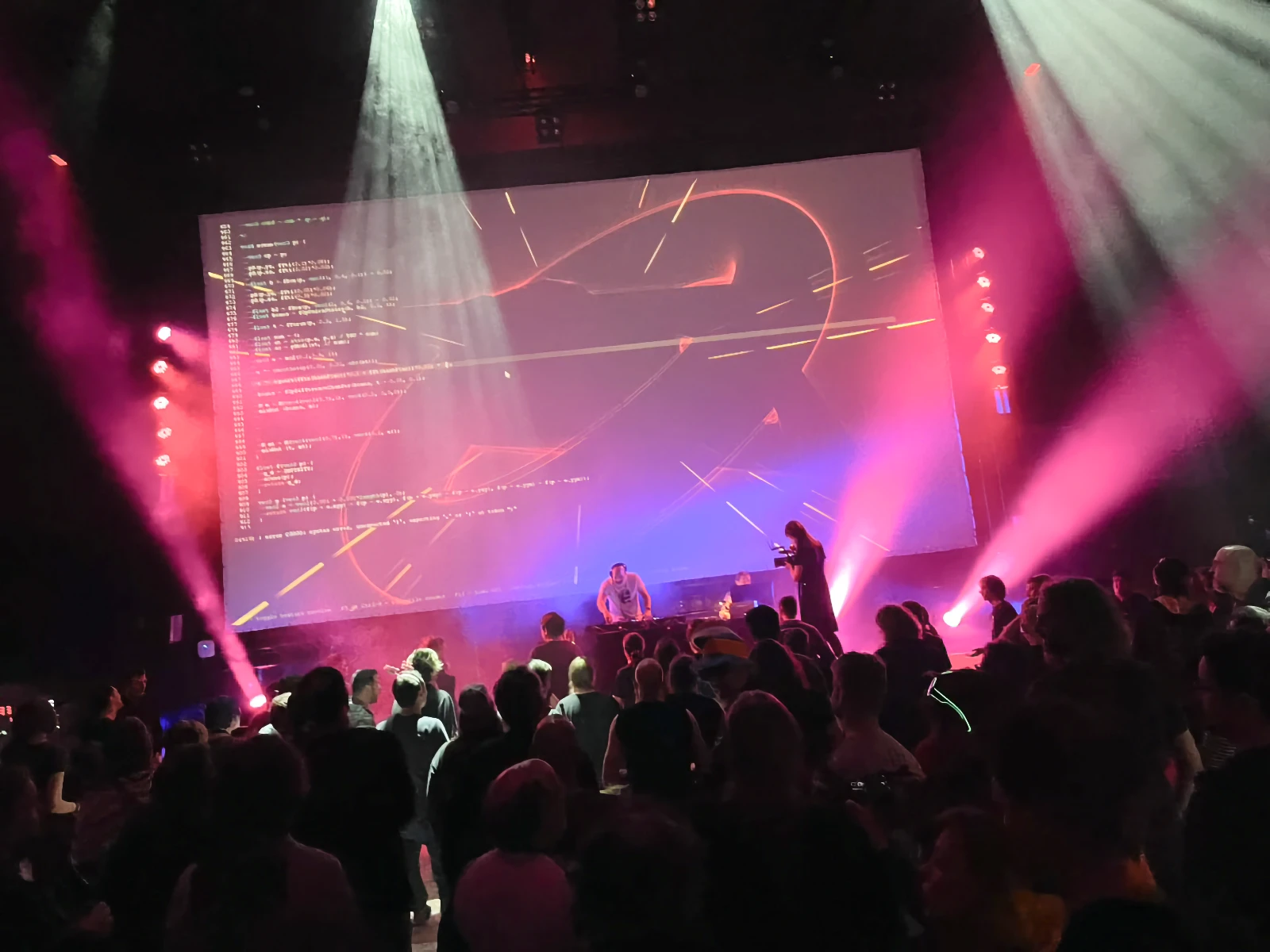 A DJ performing with stage lights and a dancing crowd at Revision.