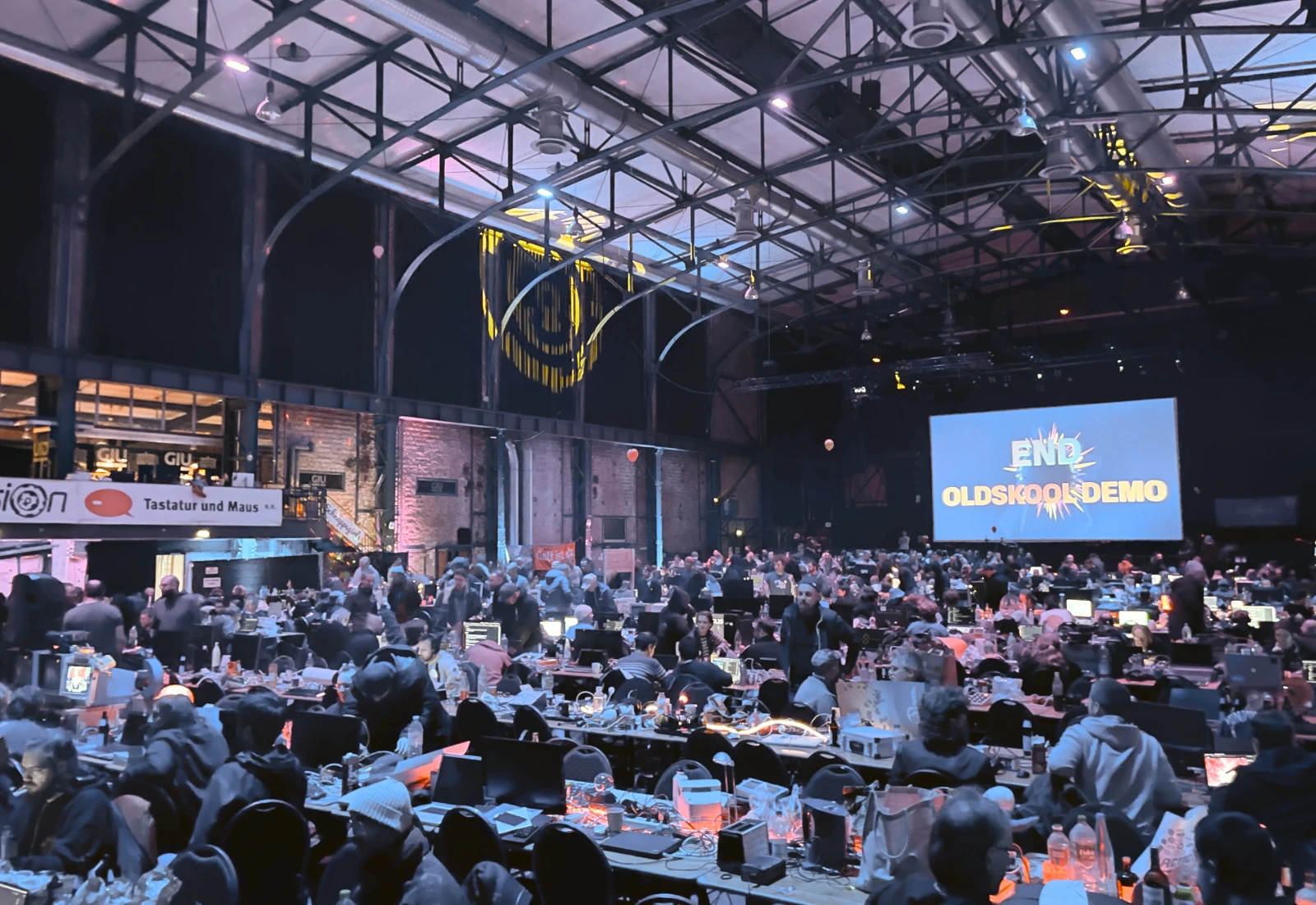 The main hall during competitions with many sceners and a large projection screen.